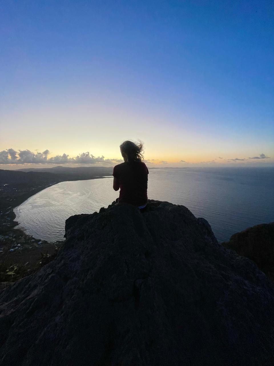 Lora Kergomard contemplant la baie depuis un sommet au coucher du soleil